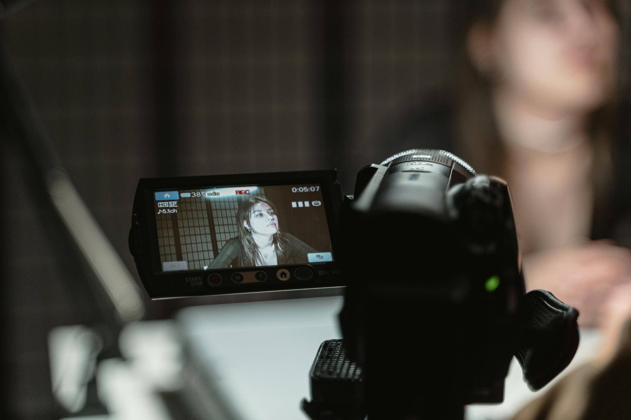 Close-up of a camera capturing a woman during a video shoot indoors.