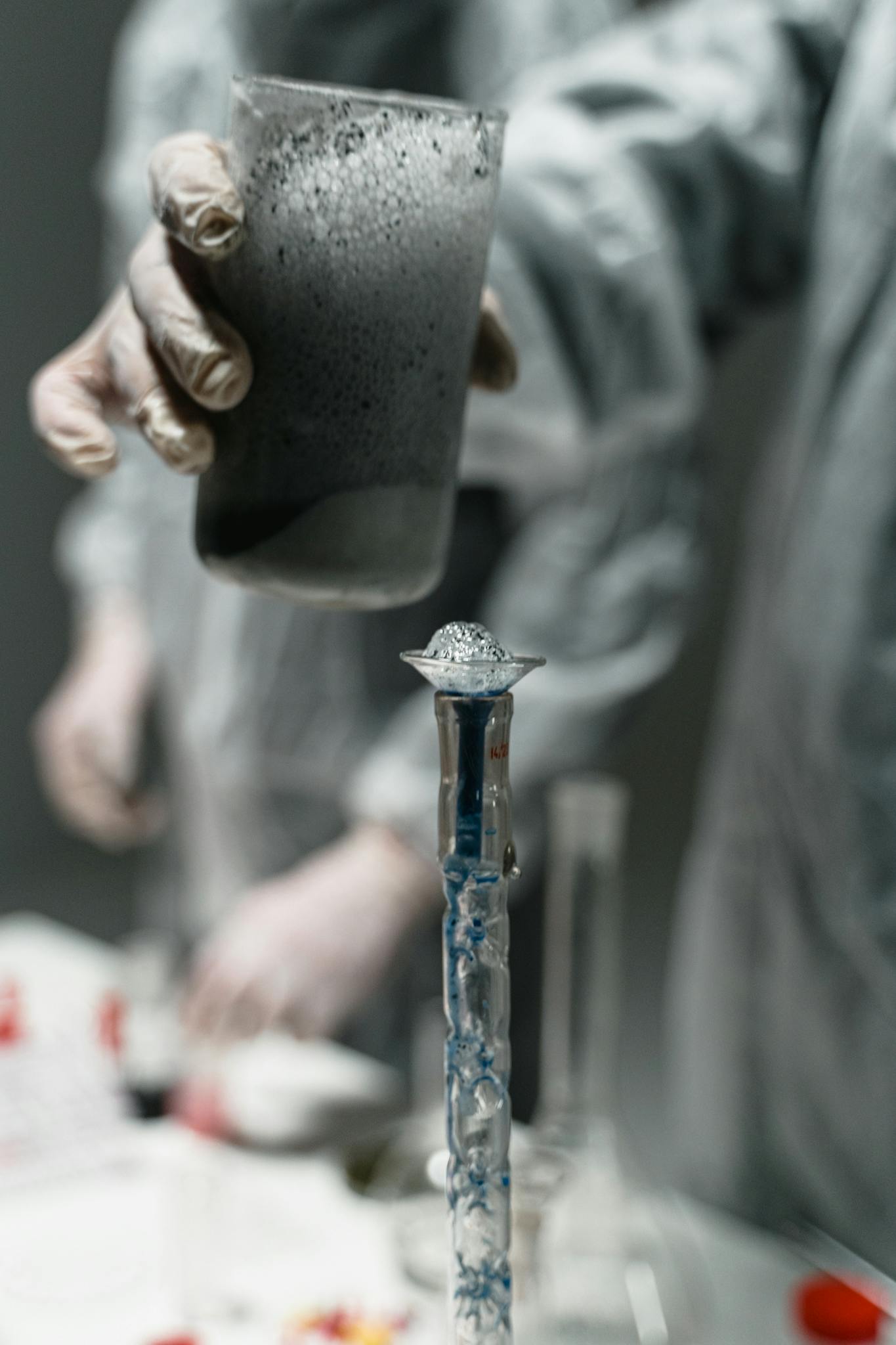 Lab experiment with liquid pouring into test tube, scientific research setting.